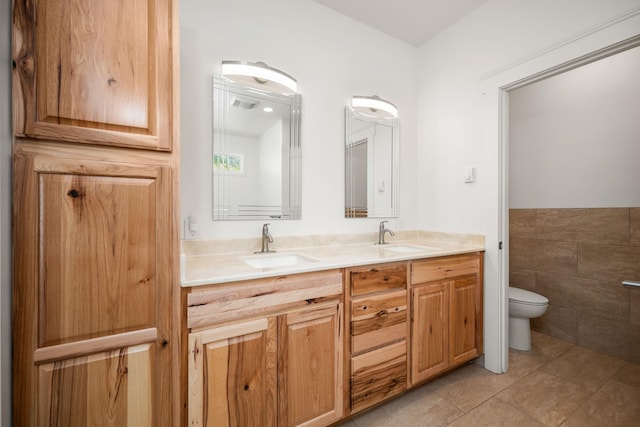 bathroom with vanity, toilet, tile patterned flooring, and tile walls