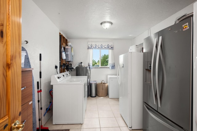 laundry room with light tile patterned flooring, washer and clothes dryer, water heater, and a textured ceiling