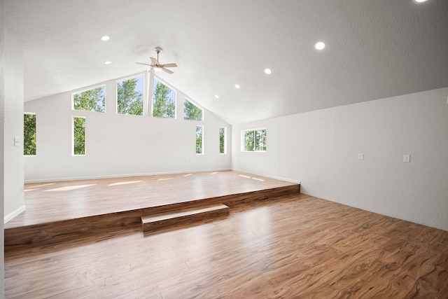 unfurnished living room with hardwood / wood-style flooring, ceiling fan, and high vaulted ceiling