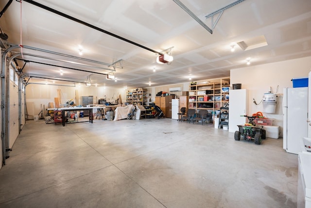 garage with white refrigerator, a garage door opener, and a workshop area