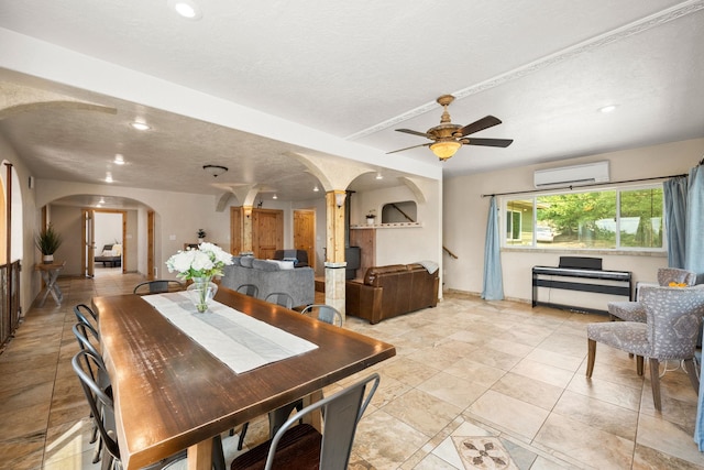 dining area with ceiling fan, a wall mounted air conditioner, decorative columns, and a textured ceiling