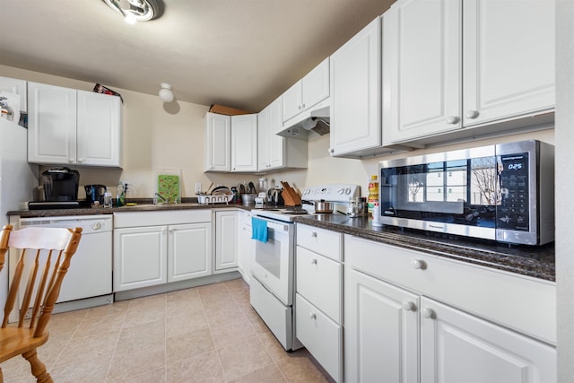 kitchen with light tile patterned flooring, sink, white cabinetry, white appliances, and dark stone counters