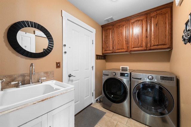 laundry area with sink, light tile patterned floors, washing machine and dryer, and cabinets