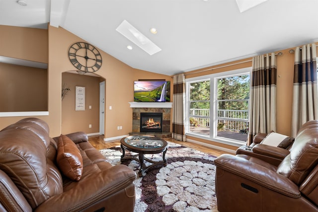 living room with a tile fireplace, wood-type flooring, and lofted ceiling with skylight