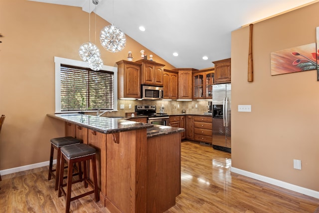 kitchen featuring pendant lighting, stainless steel appliances, tasteful backsplash, light hardwood / wood-style floors, and a chandelier