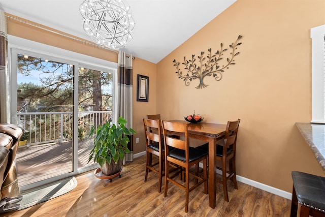 dining room featuring hardwood / wood-style flooring, lofted ceiling, and an inviting chandelier