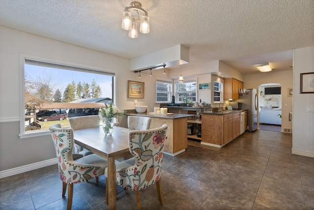 dining space featuring dark tile patterned flooring, sink, and a textured ceiling