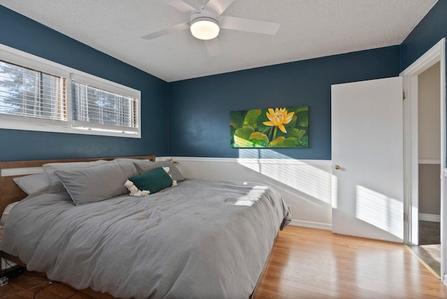 bedroom with a textured ceiling, light hardwood / wood-style floors, and ceiling fan