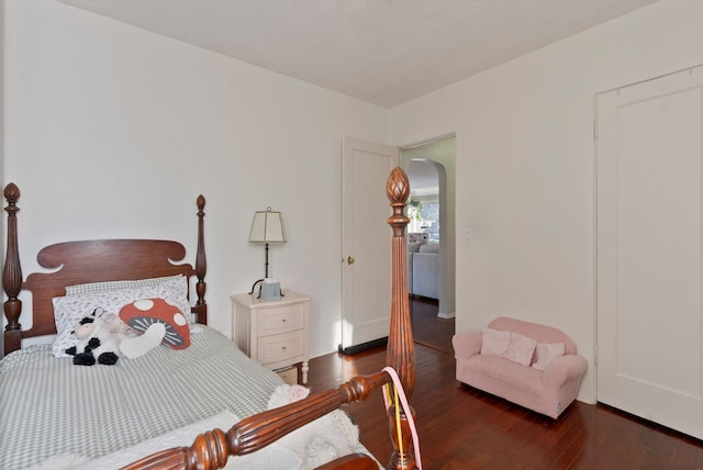 bedroom with a textured ceiling and dark hardwood / wood-style flooring