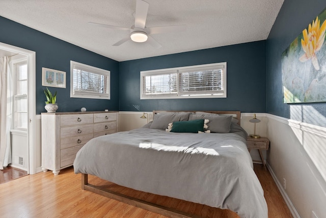 bedroom with ceiling fan, a textured ceiling, and light hardwood / wood-style flooring