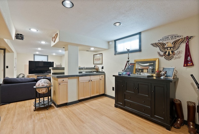 kitchen with light brown cabinetry, sink, light hardwood / wood-style flooring, and a textured ceiling