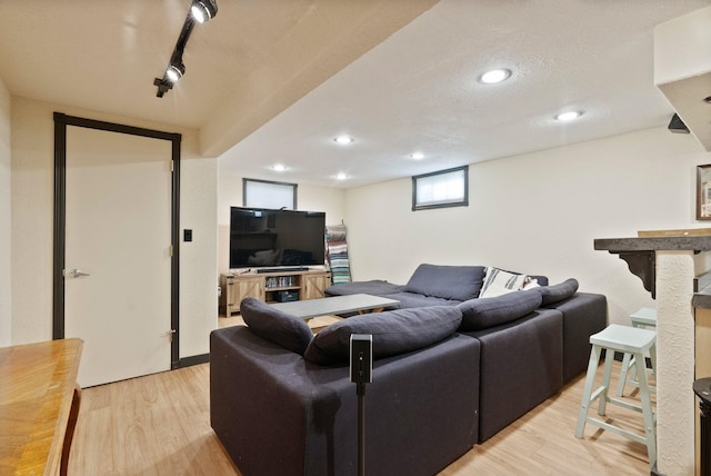 living room featuring light hardwood / wood-style flooring, rail lighting, and a textured ceiling