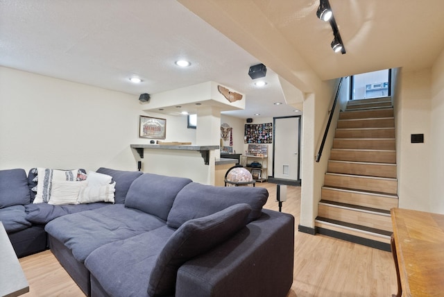 living room featuring bar area, rail lighting, and light wood-type flooring