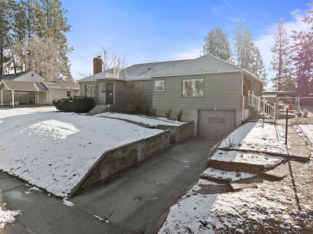 snow covered back of property with a garage