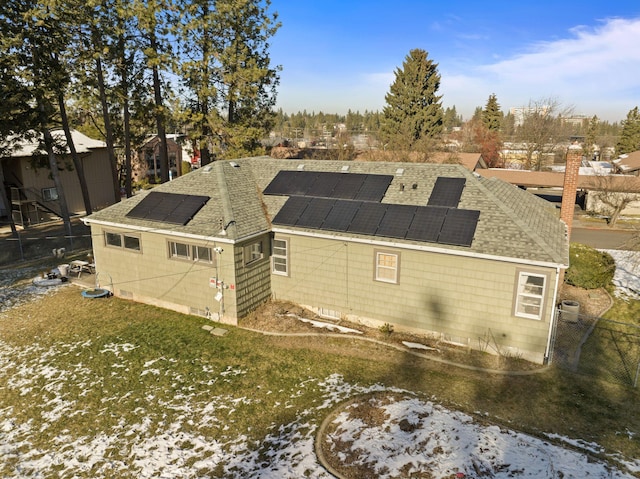 snow covered property featuring a lawn and solar panels