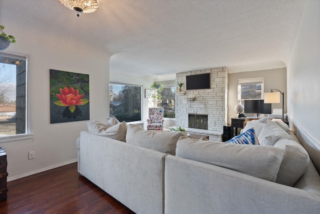 living room with dark wood-type flooring, a fireplace, and a textured ceiling