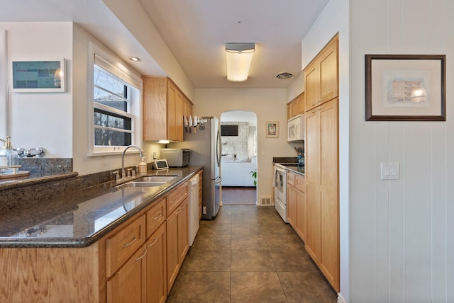 kitchen with sink, dark stone countertops, dark tile patterned flooring, and white appliances