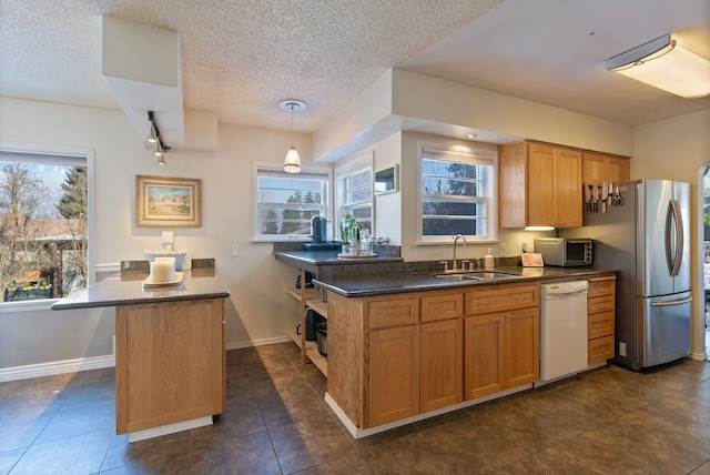 kitchen featuring sink, stainless steel fridge, hanging light fixtures, a center island, and white dishwasher