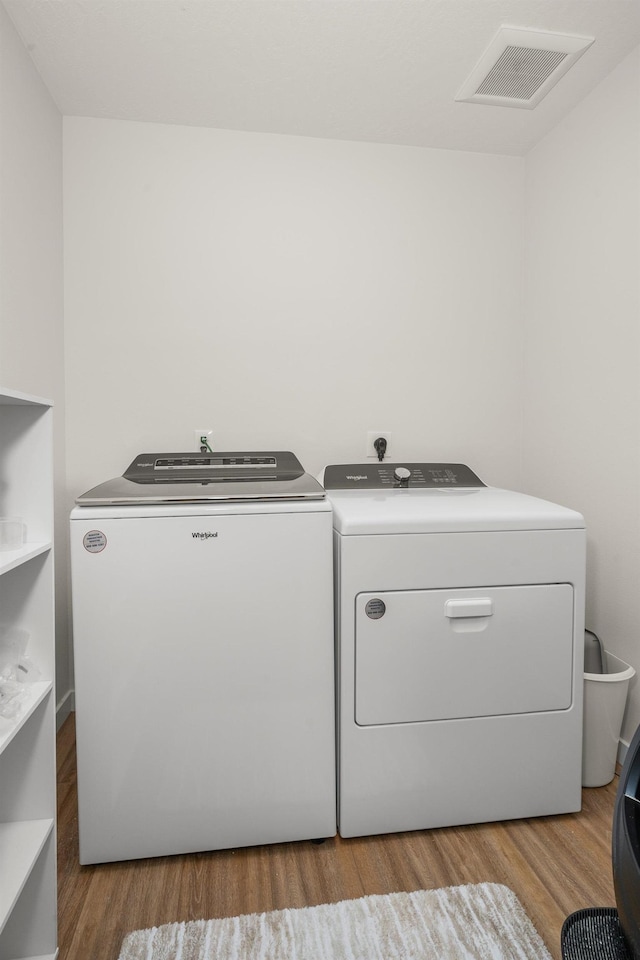 laundry room with washer and clothes dryer and light wood-type flooring