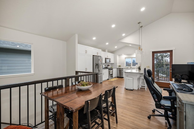 dining area featuring vaulted ceiling and light hardwood / wood-style flooring