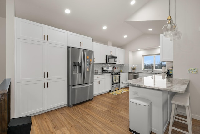 kitchen with a breakfast bar, white cabinetry, appliances with stainless steel finishes, kitchen peninsula, and pendant lighting