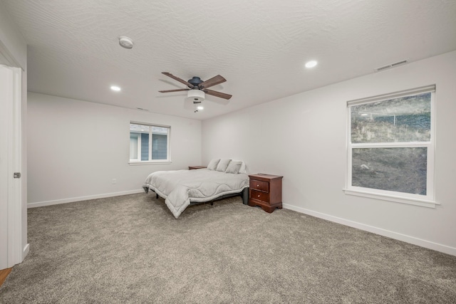 carpeted bedroom featuring ceiling fan and a textured ceiling