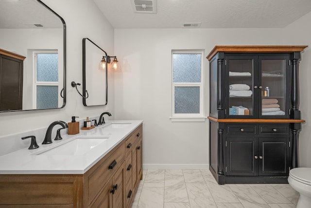 bathroom featuring vanity, a healthy amount of sunlight, a textured ceiling, and toilet