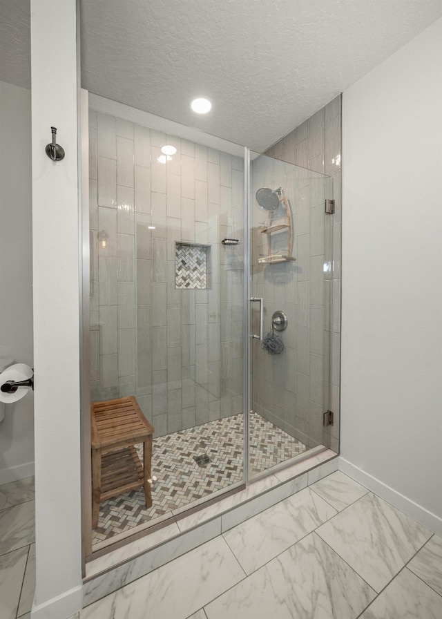 bathroom featuring a shower with shower door and a textured ceiling