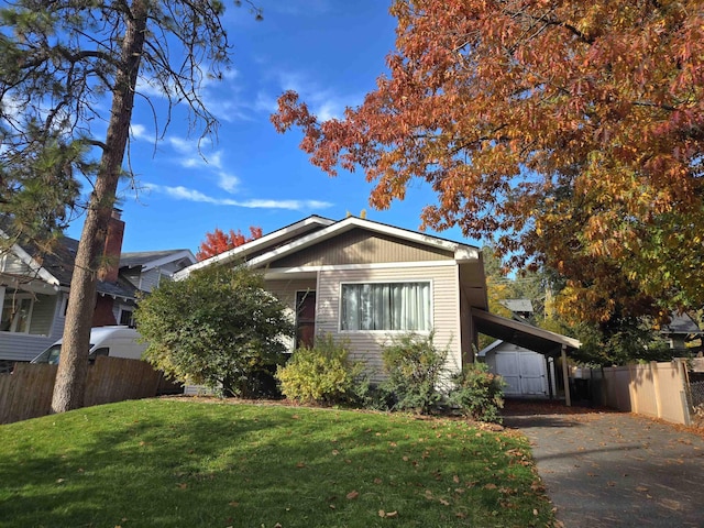 view of front of property featuring a carport, a front yard, and a storage shed