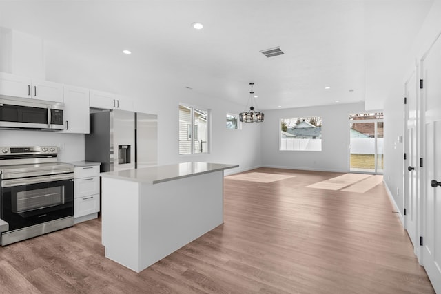 kitchen featuring white cabinetry, appliances with stainless steel finishes, decorative light fixtures, and a center island