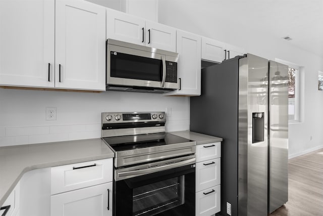 kitchen featuring stainless steel appliances, white cabinets, and light hardwood / wood-style floors