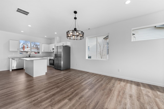 kitchen featuring a kitchen island, appliances with stainless steel finishes, dark hardwood / wood-style floors, decorative light fixtures, and white cabinetry