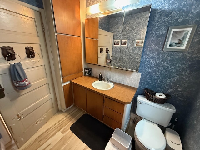 bathroom with wood-type flooring, toilet, decorative backsplash, and vanity