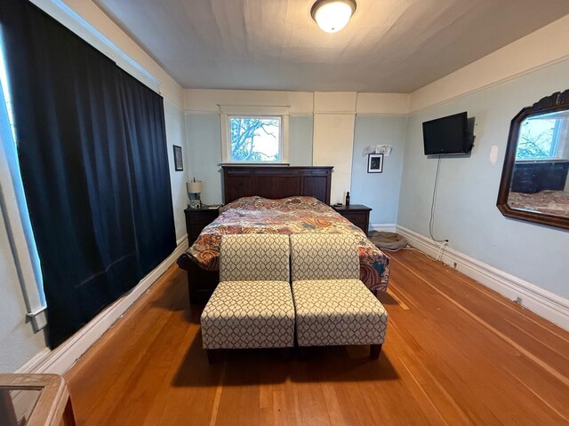 bedroom with wood-type flooring and multiple windows