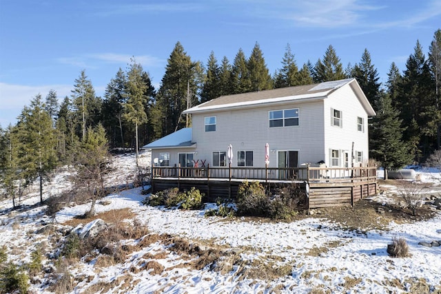 snow covered back of property featuring a wooden deck