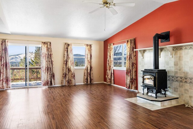 unfurnished living room featuring a healthy amount of sunlight, a mountain view, hardwood / wood-style floors, and a wood stove