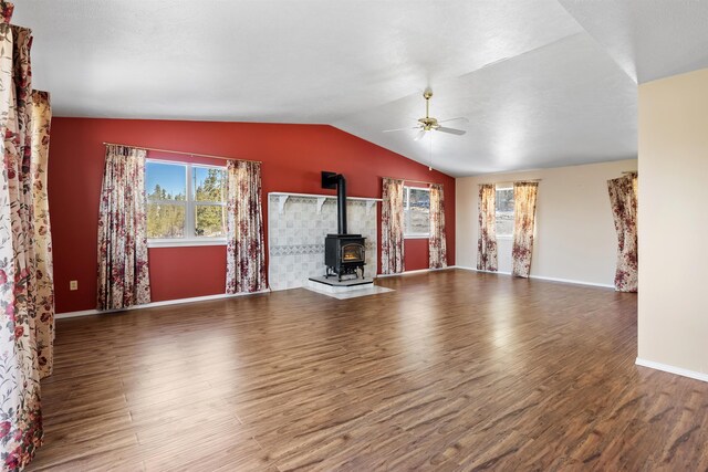 unfurnished living room with ceiling fan, lofted ceiling, wood-type flooring, and a wood stove