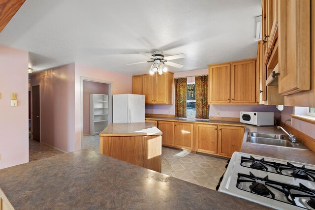 kitchen featuring ceiling fan, a center island, sink, and white appliances