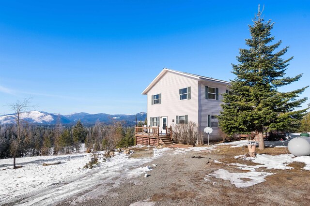 view of snowy exterior with a deck with mountain view