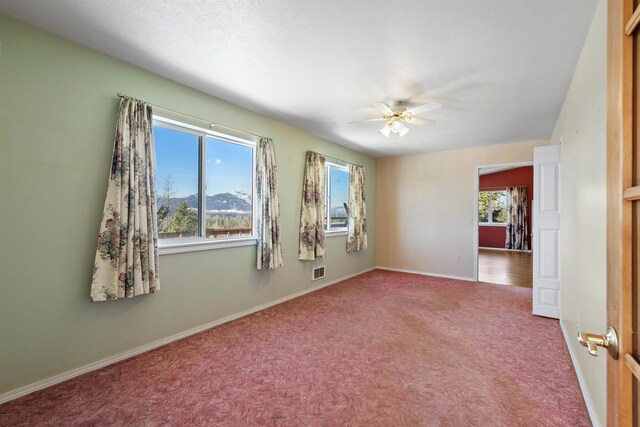 carpeted spare room with a mountain view and ceiling fan