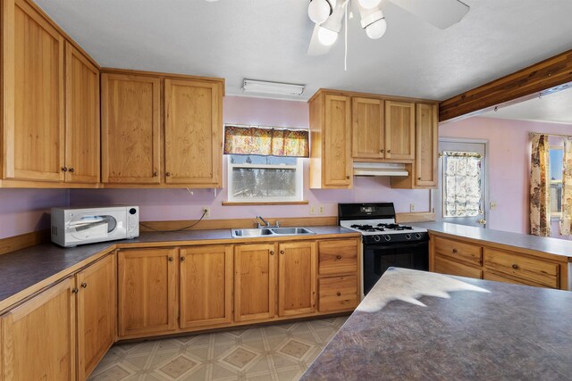 kitchen featuring ceiling fan, gas range oven, sink, and kitchen peninsula