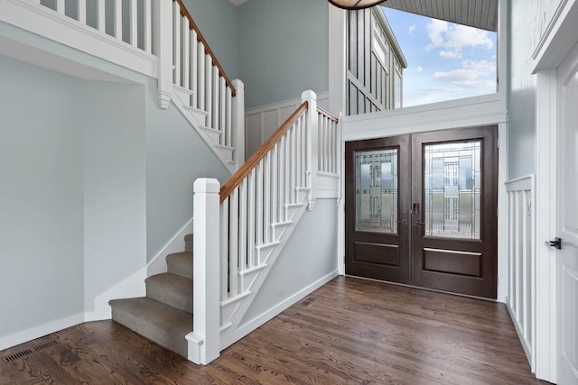 foyer with a towering ceiling, dark hardwood / wood-style flooring, and french doors