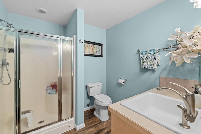 bathroom featuring a shower with door, vanity, hardwood / wood-style flooring, and toilet