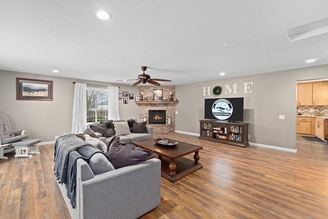 living room with ceiling fan, wood-type flooring, and a fireplace