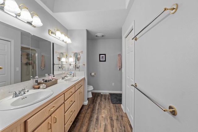 bathroom with wood-type flooring, toilet, vanity, and walk in shower