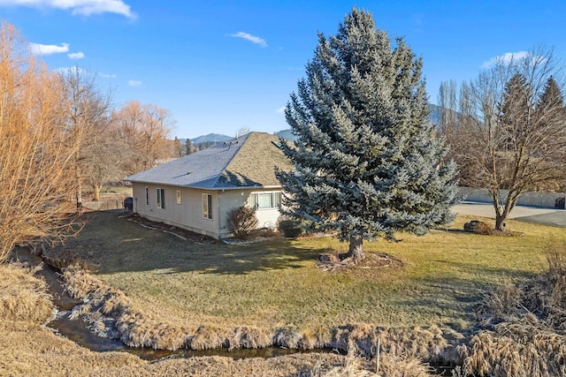 view of side of home featuring a mountain view and a lawn