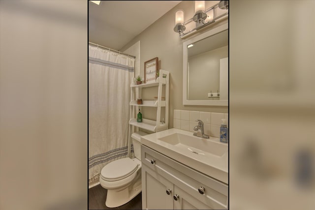 bathroom featuring tasteful backsplash, vanity, toilet, and walk in shower