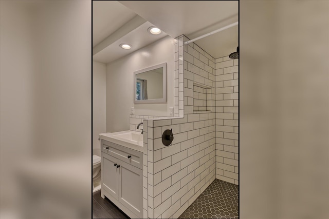 bathroom featuring vanity, a tile shower, and toilet