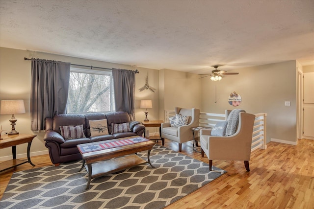 living room with ceiling fan, wood-type flooring, and a textured ceiling