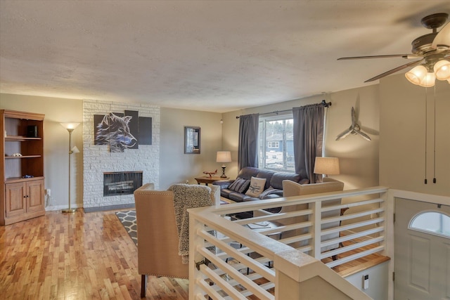 living room with hardwood / wood-style floors, a stone fireplace, and a textured ceiling